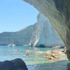 there is a boat that is in the water near some rocks and an iceberg