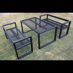 three black glass tables sitting on top of grass