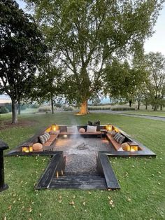 an outdoor fire pit in the middle of a grassy area with couches and tables