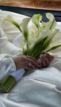 the bride is holding her wedding bouquet in her hand while she sits down on the bed