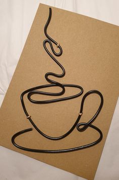 a drawing of a coffee cup on top of a piece of paper with a black cord attached to it