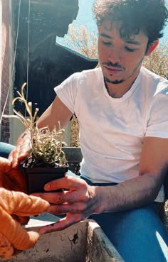 a man holding a potted plant in his hand while another person holds it up