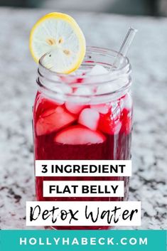 a jar filled with red liquid and ice next to a lemon slice on top of it