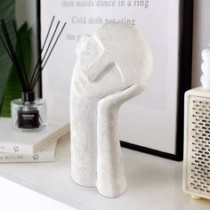 a white sculpture sitting on top of a table next to a vase and bookend