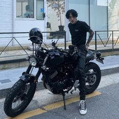 a man sitting on top of a motorcycle next to a parking space in front of a building