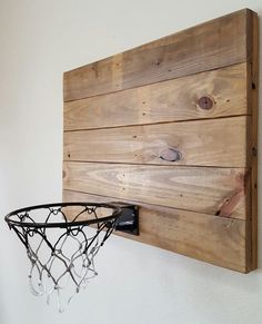 a basketball hoop mounted to the side of a wooden wall hanging on a white wall