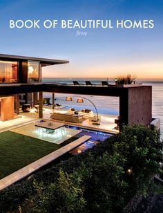 the book of beautiful homes is on display in front of an oceanfront house with grass and