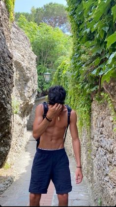 a shirtless man walking down a narrow path