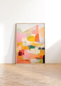 an abstract painting on the wall in a room with hard wood flooring and white walls