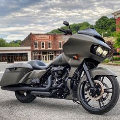 the motorcycle is parked on the side of the road near some buildings and trees in the background