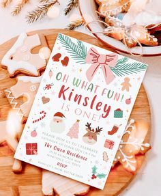 a christmas card on a plate next to some cookies and other holiday decorations with the words oh what fun kinsley is one