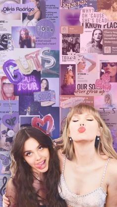 two beautiful women standing next to each other in front of a wall covered with posters