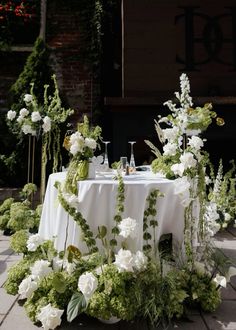 the table is set with white flowers and greenery