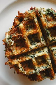 a white plate topped with waffles covered in cheese and spinach toppings