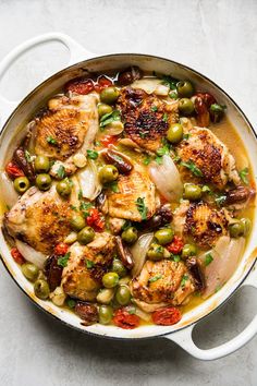 a pan filled with chicken, olives and onions