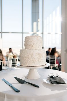 a white wedding cake sitting on top of a table next to silverware and utensils