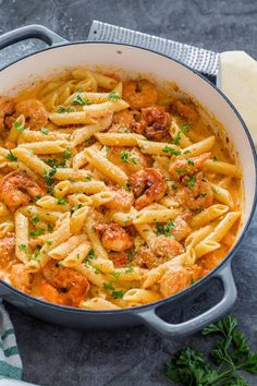 pasta with sausage and parsley in a large pot on a table next to bread