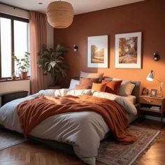 a bedroom with a large bed covered in orange blankets and throw pillows on top of it