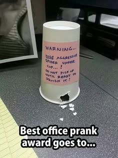 a coffee cup with writing on it sitting in front of a computer monitor and the caption best office prank award goes to