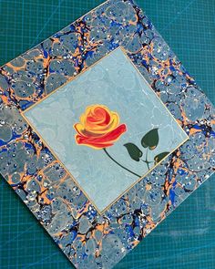 a blue and orange tile with a flower on it