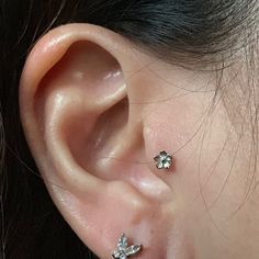 a close up of a person's ear with three piercings