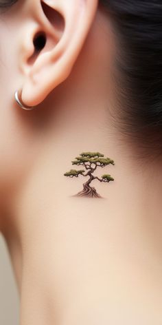 A stylish, minimalistic bonsai tattoo finds its home behind the ear, subtly echoing the wearer's love for nature. Dive into our 'TreeTee' Etsy shop – every tee bought assists in our tree-planting endeavor, aligning your fashion statement with a healthier Earth. Bonsai Tattoo Minimalist, Bonsai Tattoos, Bonsai Tree Tattoo, Tattoo Behind The Ear, Plant Tattoos, Yang Tattoo