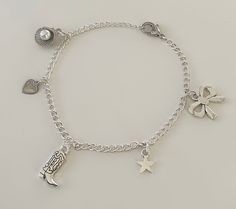 This Coastal Cowgirl Silver Charm Bracelet is the perfect accessory for every outfit. This dainty bracelet boasts an eclectic mix of charms, including a cowgirl boot charm for the coastal cowgirl, a delicate heart charm, a chic bow charm, a radiant star charm, and a seashell charm that ties all the pieces together. Get this charm bracelet for everyday wear or for the perfect gift! Charm Jewelry Silver, Silver Charm Bracelets, Silver Charm Bracelet Aesthetic, Adjustable Metal Charm Bracelet, Cute Style, Charm Bracelet Silver, Silver Charm Bracelet For The Beach, Themed Silver Charm Bracelet, Silver Adjustable Charm Bracelet For Beach, Western Charm Bracelet