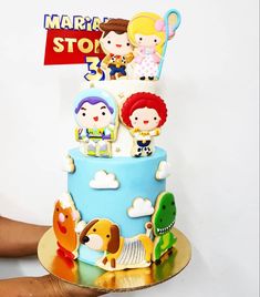 a hand holding a cake with cartoon figures on it