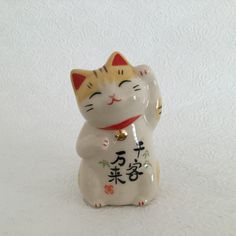 a white and yellow cat figurine with chinese writing on it's chest