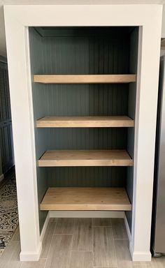 empty shelves in the corner of a room with tile flooring and wood trim on the walls