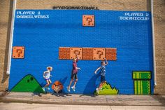 three children jumping up and down in front of a wall with video game characters painted on it