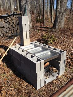 an outdoor fire pit made out of cinder blocks in the woods next to a pile of logs