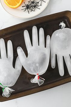 three plastic gloves on a tray with orange slices and spider webs in the background