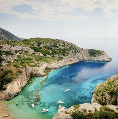 the water is crystal blue and there are several boats in it on the ocean shore