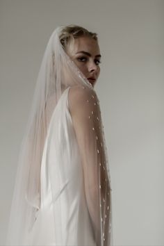 a woman wearing a white veil with pearls on it