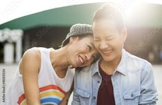 two women are laughing while looking at a cell phone