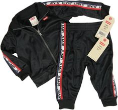 Brand new Levi's track suit with jacket & matching pants, in toddler size 12 Months.  The suit is has a black track jacket with red, white, & blue tape down the shoulders/arms and the pants are black with the red, white, & blue tape down the sides.   The track jacket features a ribbed collar and cuffs, a red tab on the left side, a full zip front, and a small batwing print on the left chest.  Pants have an elastic waistband and ribbed cuffs.  Great looking tracksuit set, perfect as a lighter-weight outer layer;  don't miss out. Detailed with a Levi's logo graphic, this toddler boys' tracksuit pairs a stand collar jacket with elastic pants. Jacket: Smooth tricot fabric Stand collar Long sleeves Tape accents down the arms Front zipper closure. Pants: Smooth tricot fabric Tape accents down th Fall Sports Sets Sportswear, Fall Sportswear Sets For Sports, Sporty Fall Sports Sets, Sporty Sets For Fall Sports, Sporty Sets For Fall, Sporty Fitted Sets For Playwear, Jacket Pants Outfit, Suit With Jacket, Tapered Joggers