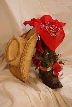 a cowboy's hat and boot are on a white sheet with red ribbon around it