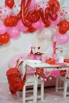 a pink couch and table in front of a wall with balloons that spell out the word love