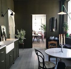 an open door leading to a dining room and kitchen area with black walls, white flooring and wooden floors