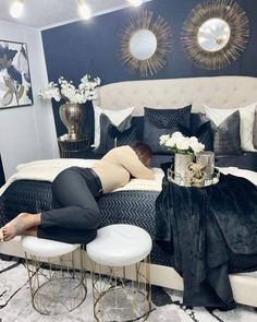 a woman laying on top of a bed in a room with blue walls and white furniture