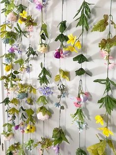 flowers are hanging on the wall with green leaves