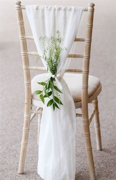 a chair with a white cloth draped over it and flowers on the back of it