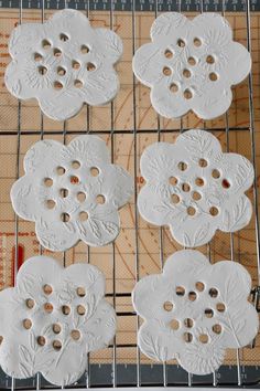 four white flower shaped cookies sitting on top of a cooling rack