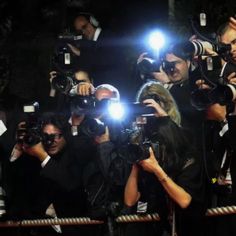 a group of people standing around each other in front of cameras and holding up their cell phones