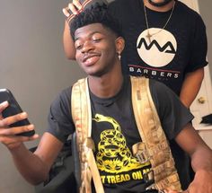 two young men standing next to each other holding cell phones