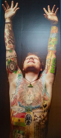 a man with lots of tattoos on his body and hands above his head is looking up at the sky