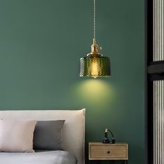 a bedroom with green walls and a white bed in front of a wall mounted light