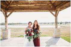 two beautiful women standing next to each other in front of a gazebo with flowers