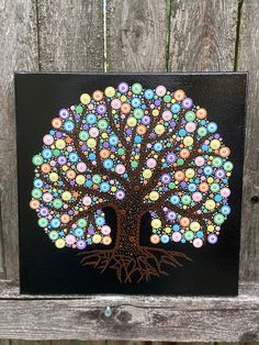 a painted tree on a wooden fence with lots of colorful balls in the shape of a tree